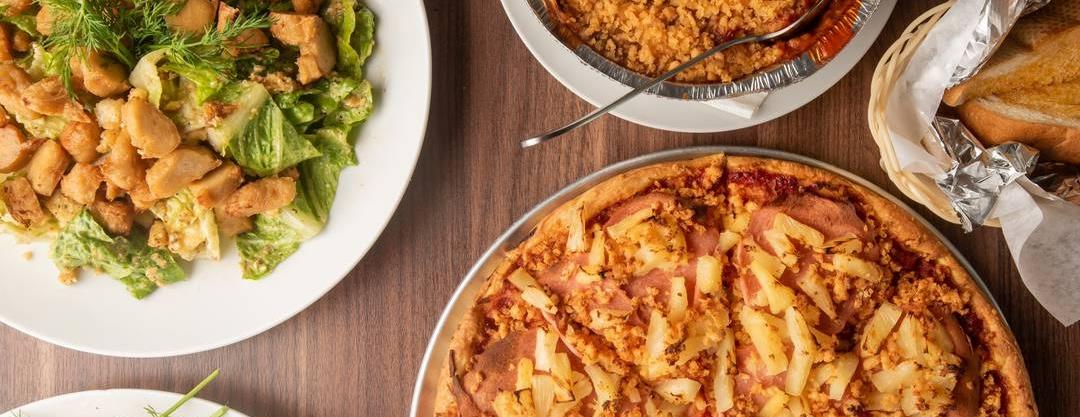 Pizza, salad, pasta, and bread arranged for sharing